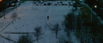 Movie still from “The Bourne Supremacy” (2004), directed by Paul Greengrass – A person walking in the snow near a parking lot; Extreme Wide shot, Overhead angle