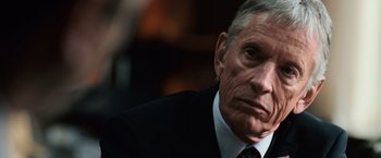 Movie still from “The Bourne Ultimatum” (2007), directed by Paul Greengrass – An older man wearing a suit and tie; Close Up shot, Over the shoulder angle