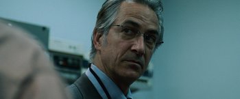 Movie still from “The Bourne Ultimatum” (2007), directed by Paul Greengrass – An older man wearing glasses and a suit; Close Up shot, Low angle