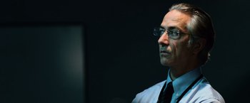 Movie still from “The Bourne Ultimatum” (2007), directed by Paul Greengrass – An older man wearing glasses and a shirt and tie; Close Up shot, Low angle