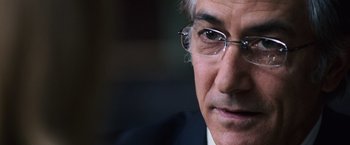 Movie still from “The Bourne Ultimatum” (2007), directed by Paul Greengrass – An older man wearing glasses and wearing a suit; Close Up shot, Over the shoulder angle