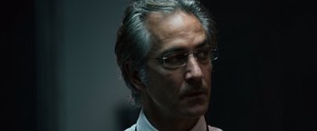Movie still from “The Bourne Ultimatum” (2007), directed by Paul Greengrass – An older man wearing glasses looking to his left; Close Up shot, Low angle