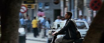 Movie still from “The Bourne Ultimatum” (2007), directed by Paul Greengrass – A man riding a scooter down the street; Wide shot, Low angle
