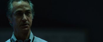 Movie still from “The Bourne Ultimatum” (2007), directed by Paul Greengrass – An older man wearing glasses is smiling for the camera; Close Up shot, Low angle