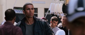 Movie still from “The Bourne Ultimatum” (2007), directed by Paul Greengrass – A man standing next to another man wearing a black jacket; Close Up shot, Over the shoulder angle