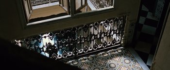 Movie still from “The Bourne Ultimatum” (2007), directed by Paul Greengrass – A balcony with a wrought - iron railing in the middle of a room; Wide shot, Overhead angle