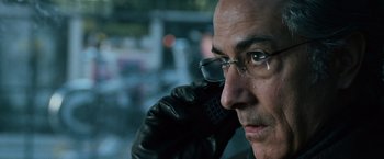 Movie still from “The Bourne Ultimatum” (2007), directed by Paul Greengrass – A person wearing glasses and a leather jacket; Close Up shot, Over the shoulder angle