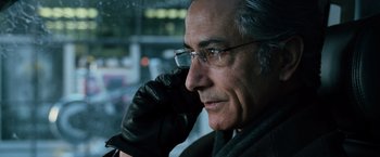 Movie still from “The Bourne Ultimatum” (2007), directed by Paul Greengrass – An older man wearing glasses and a black leather glove; Close Up shot, Low angle