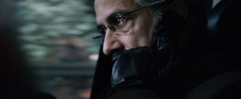 Movie still from “The Bourne Ultimatum” (2007), directed by Paul Greengrass – An older man wearing glasses and a leather jacket; Close Up shot, Over the shoulder angle