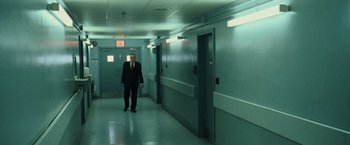 Movie still from “The Bourne Ultimatum” (2007), directed by Paul Greengrass – A man in a suit and tie standing in a hallway; Wide shot, High angle