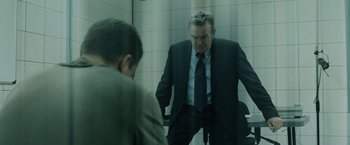 Movie still from “The Bourne Ultimatum” (2007), directed by Paul Greengrass – A man standing in front of a mirror in a room; Medium shot, Over the shoulder angle