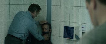 Movie still from “The Bourne Ultimatum” (2007), directed by Paul Greengrass – A man with his hands tied to his face and a man with his hands tied to his neck and head; Medium shot, Over the shoulder angle