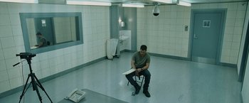 Movie still from “The Bourne Ultimatum” (2007), directed by Paul Greengrass – A man sitting on a chair in a room; Wide shot, High angle