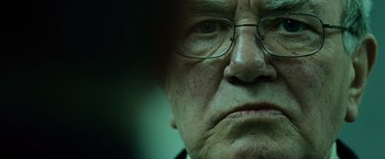 Movie still from “The Bourne Ultimatum” (2007), directed by Paul Greengrass – An old man with glasses looking at the camera; Extreme Close Up shot, Over the shoulder angle