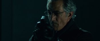 Movie still from “The Bourne Ultimatum” (2007), directed by Paul Greengrass – An older man wearing glasses and a black jacket; Close Up shot, Low angle