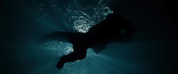 Movie still from “The Bourne Ultimatum” (2007), directed by Paul Greengrass – A person swimming in a body of water at night; Wide shot, Overhead angle