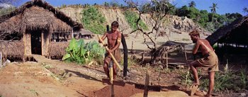 Movie still from “The Bridge on the River Kwai” (1957), directed by David Lean – A man using a wooden stick to dig a hole in the ground; Wide shot, High angle