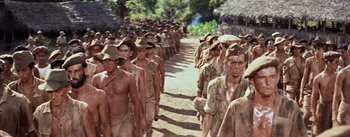 Movie still from “The Bridge on the River Kwai” (1957), directed by David Lean – A large group of men are walking down a dirt road; Wide shot, High angle