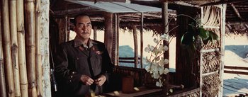 Movie still from “The Bridge on the River Kwai” (1957), directed by David Lean – An older man standing in front of a table; Medium shot, Low angle