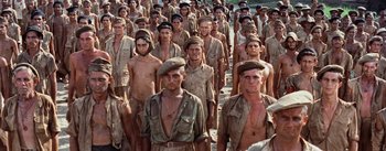 Movie still from “The Bridge on the River Kwai” (1957), directed by David Lean – A large group of men standing in the sand; Medium shot, High angle