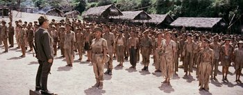 Movie still from “The Bridge on the River Kwai” (1957), directed by David Lean – A large group of men in uniform standing in a field; Wide shot, High angle