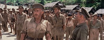 Movie still from “The Bridge on the River Kwai” (1957), directed by David Lean – A group of men walking down a street in uniforms; Medium shot, Low angle