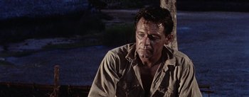 Movie still from “The Bridge on the River Kwai” (1957), directed by David Lean – A person sitting on a bench; Close Up shot, Low angle