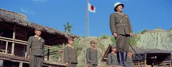 Movie still from “The Bridge on the River Kwai” (1957), directed by David Lean – A group of men standing next to each other on top of a hill; Wide shot, Low angle