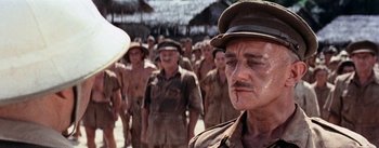 Movie still from “The Bridge on the River Kwai” (1957), directed by David Lean – A group of men standing next to each other in a line; Close Up shot, Over the shoulder angle