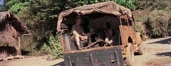 Movie still from “The Bridge on the River Kwai” (1957), directed by David Lean – Two men sitting in the back of an old truck; Wide shot, High angle