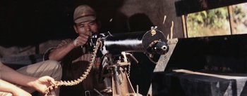 Movie still from “The Bridge on the River Kwai” (1957), directed by David Lean – A man in a brown hat is looking through a telescope; Close Up shot, Low angle