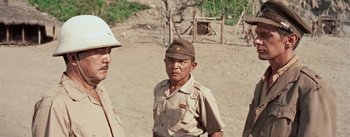 Movie still from “The Bridge on the River Kwai” (1957), directed by David Lean – A man wearing a hat and a brown uniform; Medium shot, Over the shoulder angle