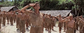 Movie still from “The Bridge on the River Kwai” (1957), directed by David Lean – An old man saluting in front of a group of young men; Medium shot, Low angle
