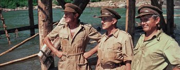 Movie still from “The Bridge on the River Kwai” (1957), directed by David Lean – A couple of men standing next to a body of water; Medium shot, Over the shoulder angle