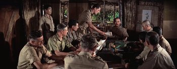 Movie still from “The Bridge on the River Kwai” (1957), directed by David Lean – A group of men sitting around a table; Medium shot, Over the shoulder angle