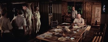 Movie still from “The Bridge on the River Kwai” (1957), directed by David Lean – Two men standing in front of a wooden table; Wide shot, High angle