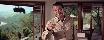 Movie still from “The Bridge on the River Kwai” (1957), directed by David Lean – A man holding a shot glass in his hand; Medium shot, Low angle