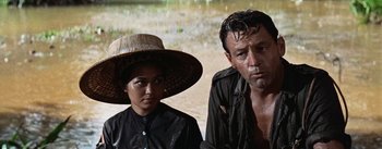 Movie still from “The Bridge on the River Kwai” (1957), directed by David Lean – A man and a woman wearing a hat and looking at the camera; Close Up shot, Low angle