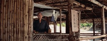 Movie still from “The Bridge on the River Kwai” (1957), directed by David Lean – A man standing inside of a wooden hut; Medium shot, Low angle