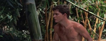 Movie still from “The Bridge on the River Kwai” (1957), directed by David Lean – A shirtless man standing in front of a bunch of trees; Close Up shot, Over the shoulder angle