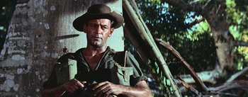 Movie still from “The Bridge on the River Kwai” (1957), directed by David Lean – A man in a hat holding a rifle and looking at the camera; Medium shot, Low angle