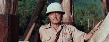 Movie still from “The Bridge on the River Kwai” (1957), directed by David Lean – A man wearing a white hat and a brown shirt; Close Up shot, Low angle