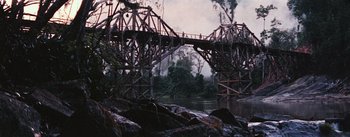 Movie still from “The Bridge on the River Kwai” (1957), directed by David Lean – An old wooden bridge over a body of water; Extreme Wide shot, Low angle