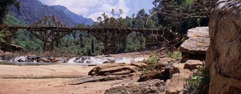 Movie still from “The Bridge on the River Kwai” (1957), directed by David Lean – A bridge over a river with trees in the background; Extreme Wide shot, High angle