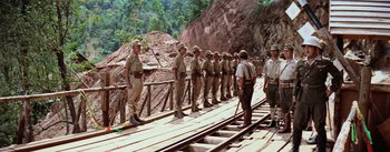 Movie still from “The Bridge on the River Kwai” (1957), directed by David Lean – A group of men standing next to each other on train tracks; Wide shot, High angle