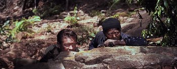 Movie still from “The Bridge on the River Kwai” (1957), directed by David Lean – Two men are hiding in the rocks while looking through binoculars; Medium shot, High angle