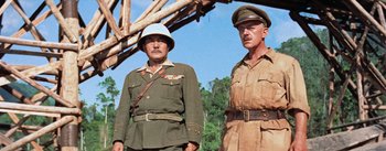 Movie still from “The Bridge on the River Kwai” (1957), directed by David Lean – Two men in military uniforms standing next to each other; Medium shot, Low angle
