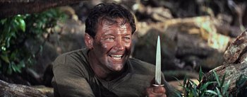 Movie still from “The Bridge on the River Kwai” (1957), directed by David Lean – A person holding a knife in his hand; Close Up shot, High angle