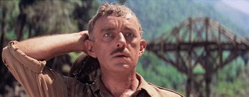 Movie still from “The Bridge on the River Kwai” (1957), directed by David Lean – An old man with a mustache is looking at the camera; Close Up shot, Low angle