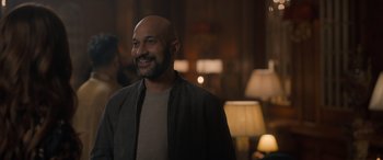 Movie still from “The Bubble” (2022), directed by Judd Apatow – A man with a bald head is smiling for the camera; Medium shot, Over the shoulder angle